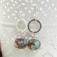 Pair of earrings with brown and blue beads on a white surface
