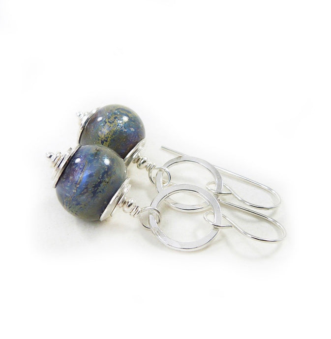 Pair of silver earrings with blue glass beads on a white background